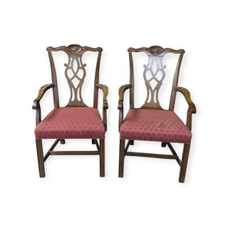 A pair of wooden arm chairs with a maroon seat upholstery and a floral pattern, viewed from the front.