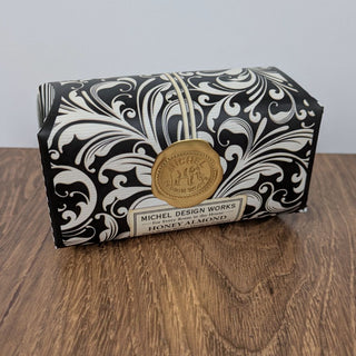 A large soap bar with a black and white allover floral print packaging, featuring a gold seal and the brand name 'Michael Design Works'.