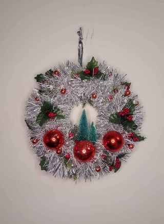 Midcentury mercury glass wreath with vintage red ornaments, mistletoe Holly Berry, bottle brush trees on silver, white tinsel