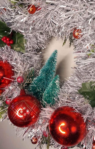 Midcentury mercury glass wreath with vintage red ornaments, mistletoe Holly Berry, bottle brush trees on silver, white tinsel