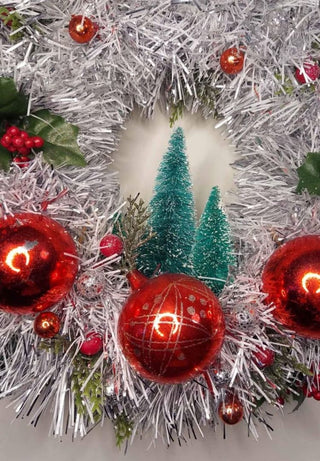 Midcentury mercury glass wreath with vintage red ornaments, mistletoe Holly Berry, bottle brush trees on silver, white tinsel