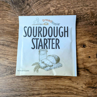 A packet of Breadtopia Sourdough Starter on a wooden surface.