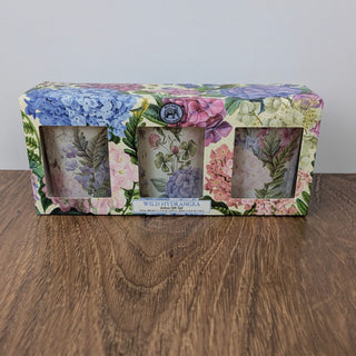 A set of three votive candles in floral gift packaging, labeled 'Wild Hydrangea' by Michel Design Works.