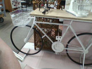 Bicycle-shaped table with a basket on a wooden floor