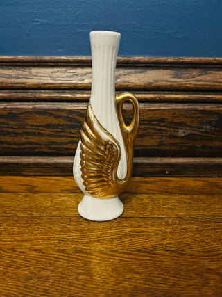 White and gold vase on a wooden surface with a blue wall background