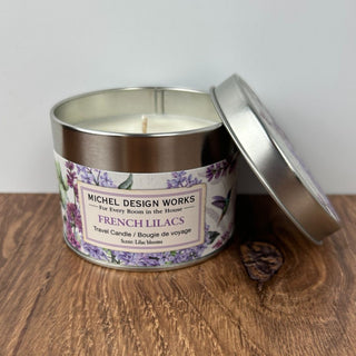 Candle in a metal tin with a label on a wooden surface