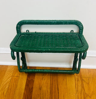 Green wicker bench on a wooden floor against a white wall