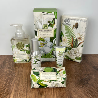 Set of Michel Design Works Magnolia Petals products on a wooden surface with a white background