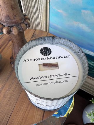 Candle with 'Anchored Northwest' label on a wooden surface