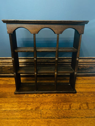 Wooden shelf with arches on a wooden floor against a blue wall